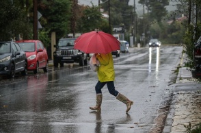 Γυναίκα με ομπρέλα και γαλότσες εν μέσω κακοκαιρίας
