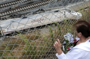 Γυναίκα αφήνει λίγα λουλούδια στο σημείο που εκτροχιάστηκε το τρένο στο Σαντιάγο ντε Κομποστέλα της Ισπανίας
