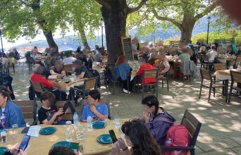 Παιδιά καθισμένα σε τραπέζι ταβέρνας με τα κινητά στο χέρι