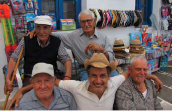 Ο Dimitris Dassios καθισμένος στο παγκάκι ανάμεσα σε φίλους στο νησί