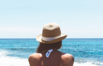 Γυναίκα με ψάθινο καπέλο κοιτάζει τη θάλασσα