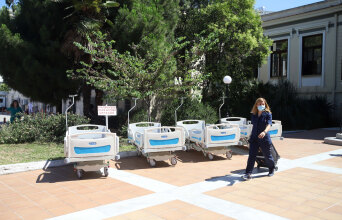 Φορεία στον προαύλιο χώρο νοσοκομείου και γυναικα με ιατρική στολή και μάσκα