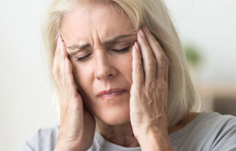 Ηλικιωμένη γυναίκα πιάνει το κεφάλι της με τα χέρια