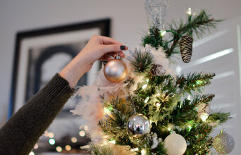 Γυναικείο χέρι αφήνει στολίδι στο χριστουγεννιάτικο δέντρο