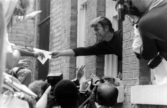 Ο Ντέιβιντ Μπόουι απλώνει το χέρι του από το παράθυρο του σπιτιού του σε θαυμαστές