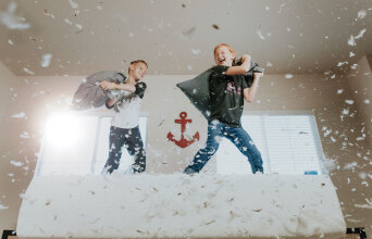 Αγόρια παίζουν μαξιλαροπόλεμο πάνω σε κρεβάτι