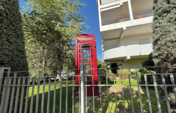Κόκκινος τηλεφωνικός θάλαμος σε αυλή πολυκατοικίας στις Τζιτζιφιές
