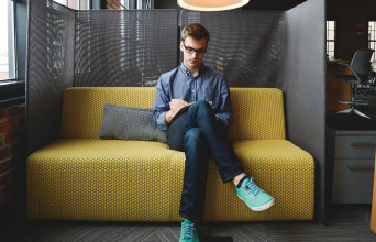 Νεαρός άντρας στον καναπέ εταιρείας, κρατάει σημειώσεις