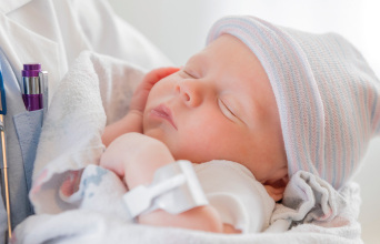 Γιατρός κρατά ένα μωρό στην αγκαλιά του