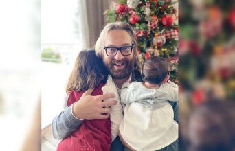Ο Ευρυπίδης Γουργουλίδης αγκαλιά με τα δύο παιδιά του μπροστά από ένα χριστουγεννιάτικο στολισμένο δέντρο