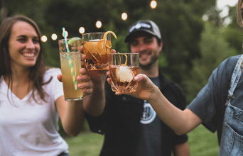 3 νεαροί φίλοι τσουκγρίζουν τα ποτήρια με το ποτό τους