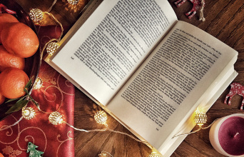 Ανοιχτό βιβλίο πάνω σε χριστουγεννιάτικα στολισμένο τραπέζι