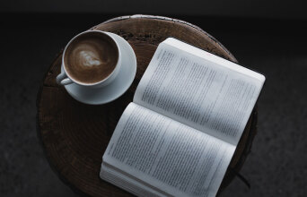 Ανοιχτό βιβλίο σε τραπεζάκι με φλιτζάνι καφέ δίπλα