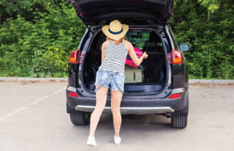 Φωτογραφία μίας γυναίκας να τοποθετεί τα πράγματά της στο πόρτμπαγκάζ.