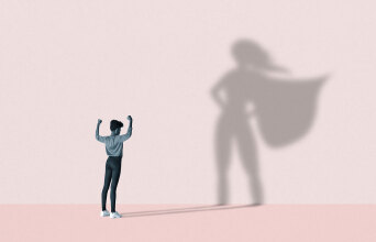 Εικονογράφηση γυναίκα που η σκιά της στον τοίχο έχει τη πόζα σουπερήρωα (μετα χέρια στη μέση και την κάπα να ανεμίζει)