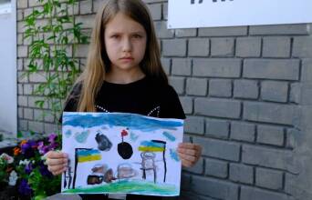 Ένα κορίτσι από την Ουκρανία κρατάει μια ζωγραφιά για τον πόλεμο της Ρωσίας στη χώρα της