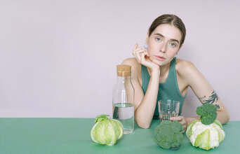 Καθιστή κοπέλα με λαχανικά μπροστά της