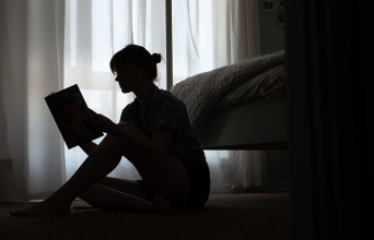 Κοπέλα καθισμένη στο πάτωμα διαβάζει βιβλίο