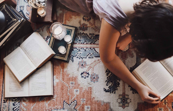 Άντρας ξαπλωμένος μπρούμυτα στο πάτωμα διαβάζει βιβλίο