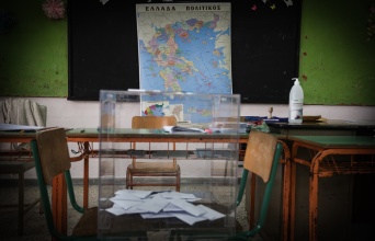 Κάλπη στερεωμένη σε δύο καρέκλες μπροστά από τον χάρτη της Ελλάδας