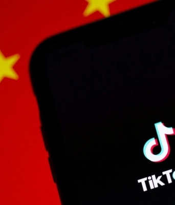 Το logo του TikTok και πίσω μία σημαία της Κίνας