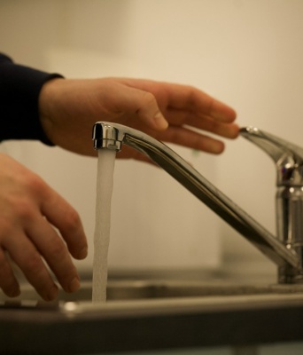 Βρύση με νερό και χέρι που πλένεται