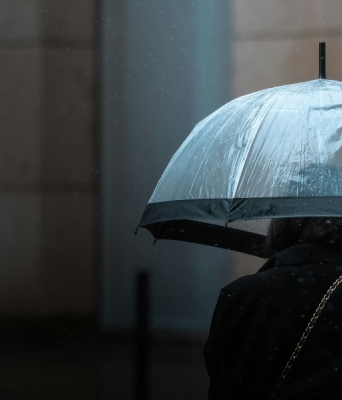 Γυναίκα κρατάει ομπρέλα μέσα στη βροχή