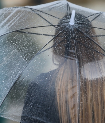 Γυναίκα κρατά ομπρέλα για να προστατευτεί από τη βροχή