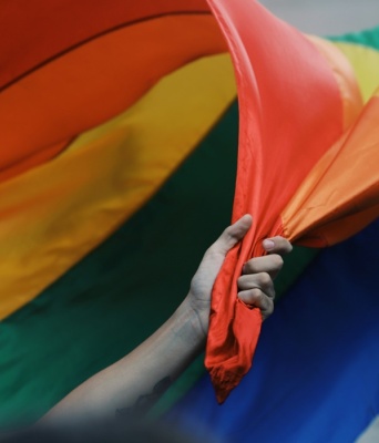 Χέρι κρατά τη σημαία της ΛΟΑΤΚΙ + κοινότητας