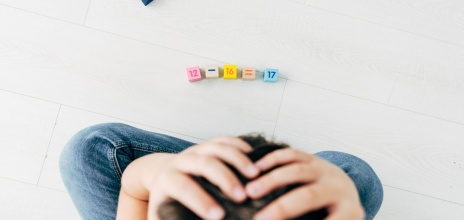 Παιδί που απελπίζεται κάνοντας υπολογισμούς αριθμητικής με τουβλάκια