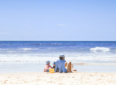 Οικογένεια κάθεται στην παραλία στην αμμουδιά
