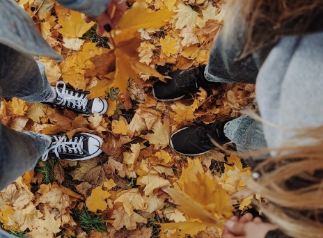 Κορίτσια στέκονται όρθια πάνω σε κιτρινισμένα, πεσμένα φύλλα δέντρων