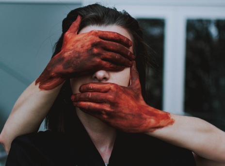 Χέρια με αίματα καλύπτουν πρόσωπο γυναίκας
