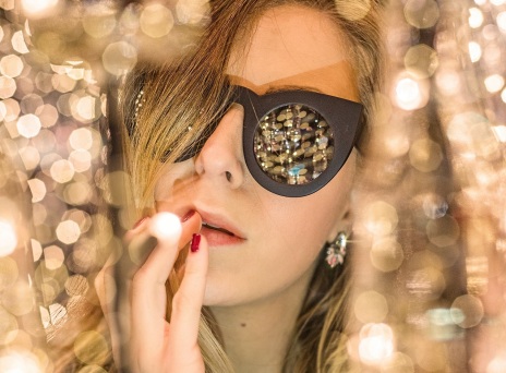 Γυναίκα με γυαλιά ηλίου ανάμεσα σε χρυσά χριστουγεννιάτικα λαμπάκια