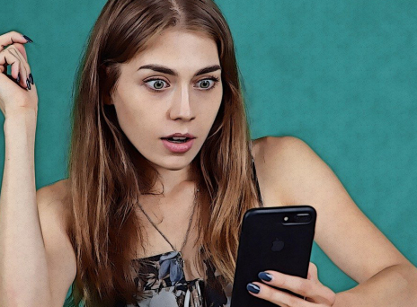 Γυναίκα κοιτάει σοκαρισμένη το κινητό της