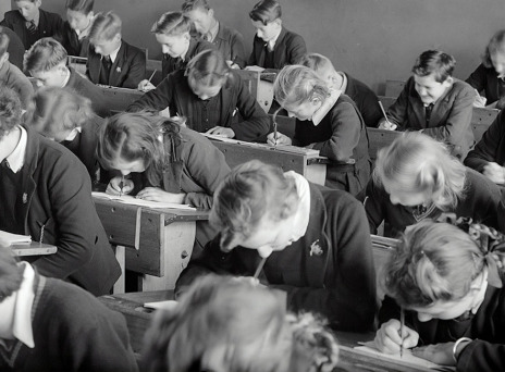 Ασπρόμαυρη φωτογραφία μαθητών σε θρανία να γράφουν διαγώνισμα