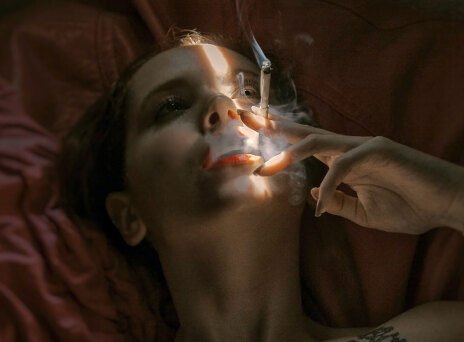 Γυναίκα ξαπλωμένη καπνίζει