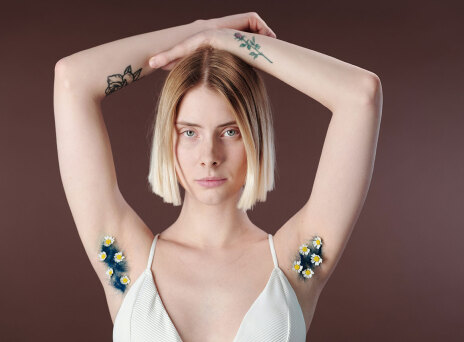 Γυναίκα με σηκωμένα χέρια και μπλε τρίχες στη μασχάλη με λουλουδάκια