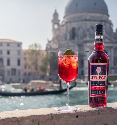 Μπουκάλι Select Aperitivo και ποτήρι Spritz Veneziano πάνω σε γέφυγα με φόντο τα κανάλια της Βενετίας