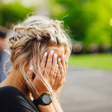 Κοπέλα κρύβει το πρόσωπό της με τα χέρια της