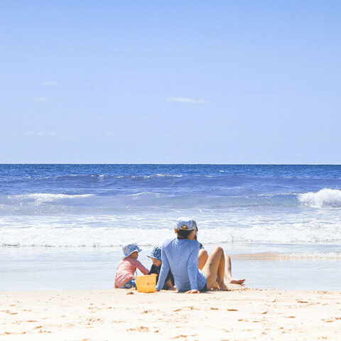 Οικογένεια κάθεται στην παραλία στην αμμουδιά