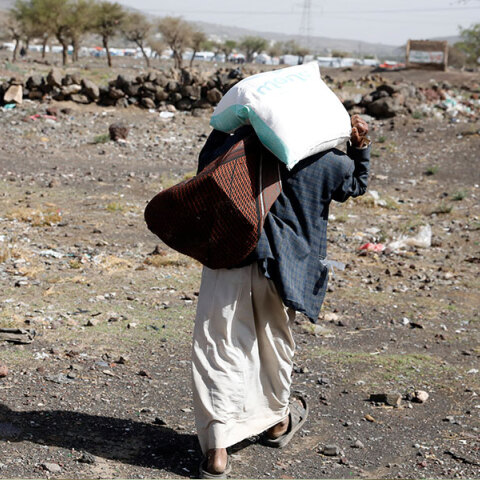 Άνδρας στην Υεμένη κουβαλά στην πλάτη ένα σακί με τρόφιμα έξω από καταυλισμό προσφύγων στην πρωτεύουσα Σαναά