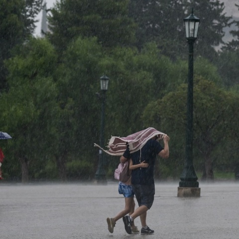 Καταιγίδα και ζευγάρι που περπατά αγκαλιασμένο προσπαθώντας να προφυλαχτεί