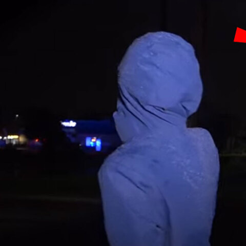 Η δημοσιογράφος στη Φλόριντα έχει γυρισμένη την πλάτη για να δει τον κυκλώνα Ίαν να ξηλώνει την πινακίδα στο εμπορικό κέντρο