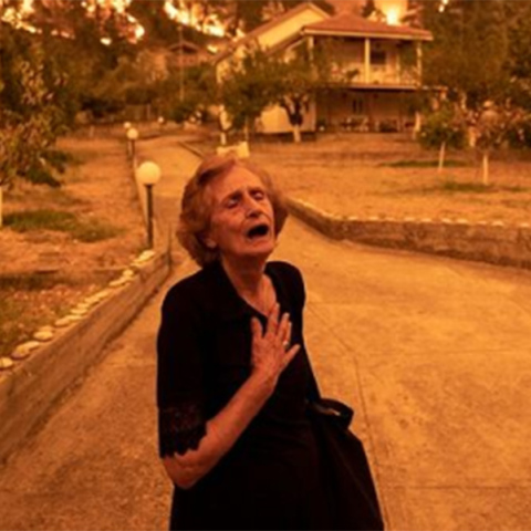Ηλικιωμένη σε απόγνωση, καθώς εγκαταλείπει το σπίτι της που τυλίγεται στις φλόγες, στο χωριό Γούβες, στη βόρεια Εύβοια