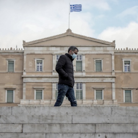 Άνδρας με μπουφάν και μάσκα μπροστά από τη Βουλή