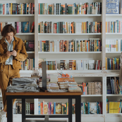 Ένας άντρας και μια γυναίκα στη βιβλιοθήκη, κοιτάνε τα κινητά τους