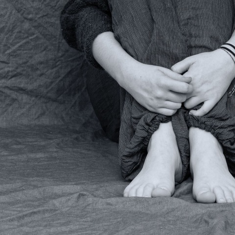 Παιδί με μαζεμένα τα πόδια κοντά στο κορμί του σε ασπρόμαυρη εικόνα που παραπέμπει σε bullying