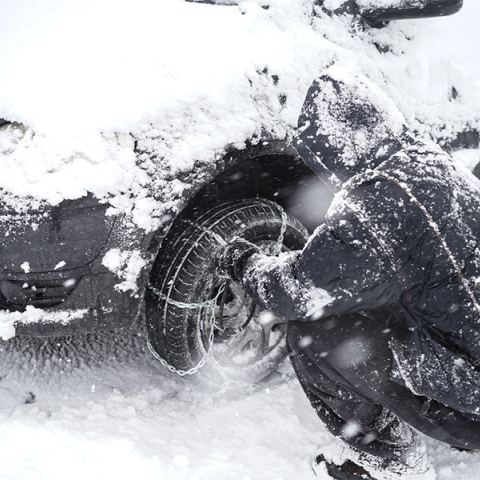 Άνδρας τοποθετεί αντιολισθητικές αλυσίδες στο όχημα του
