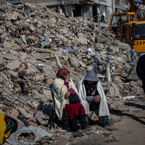 Κάτοικοι στην πόλη Χατάι της Τουρκίας κάθονται δίπλα από έναν σωρό με ερείπια μετά τον σεισμό